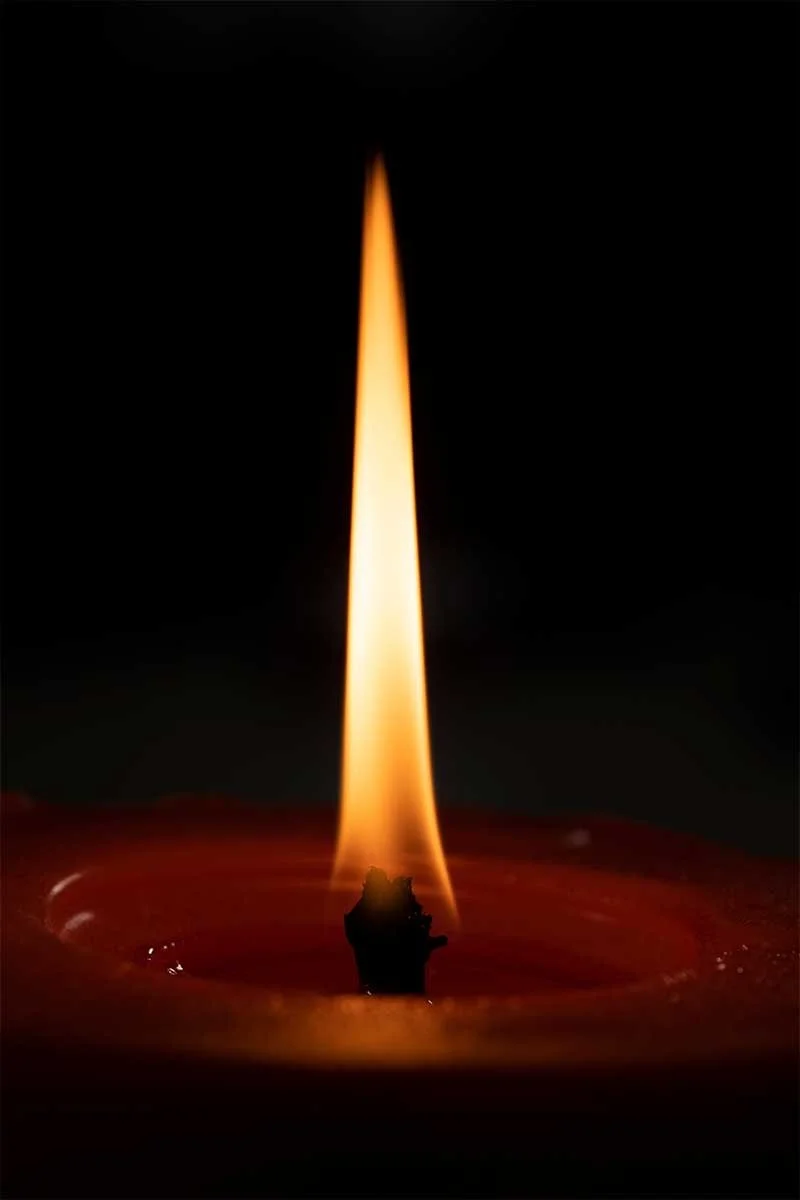 Close-up of a candle flame in a dark setting.