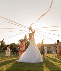 Photo d’une mariée participant au rituel du bouquet avec rubans lors d’un mariage élégant organisé par A&L Events, avec une décoration et une mise en scène sur mesure.