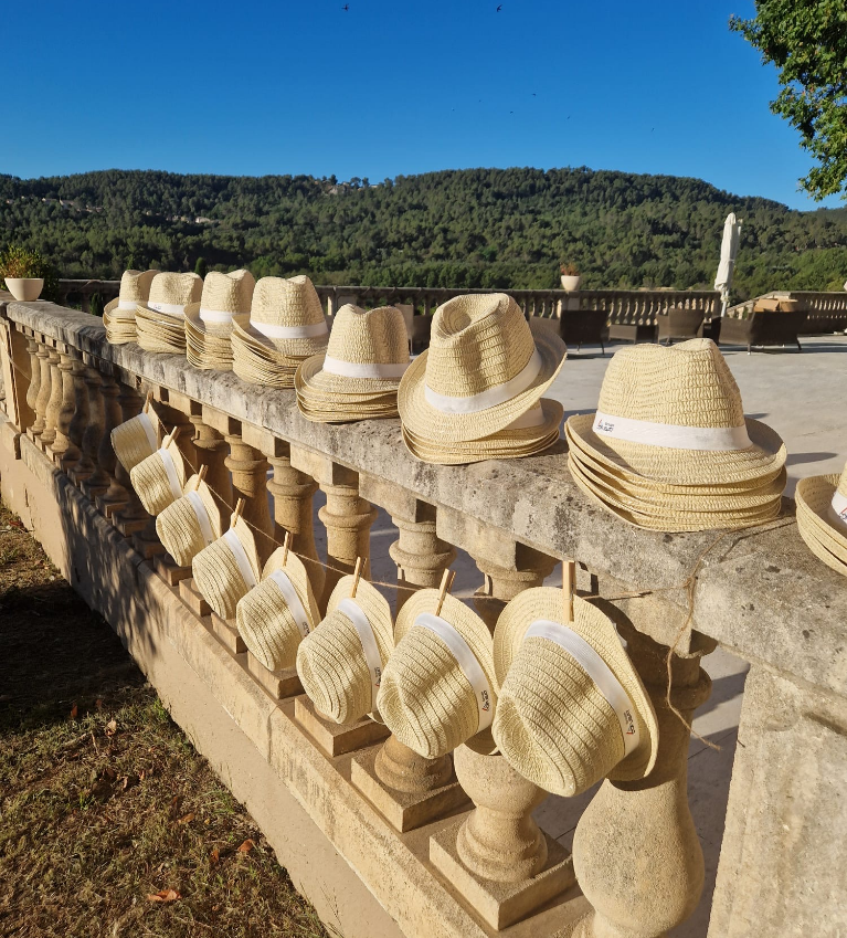Alignés sur une balustrade en pierre, des chapeaux personnalisés sont soigneusement préparer pour les collaborateurs.
