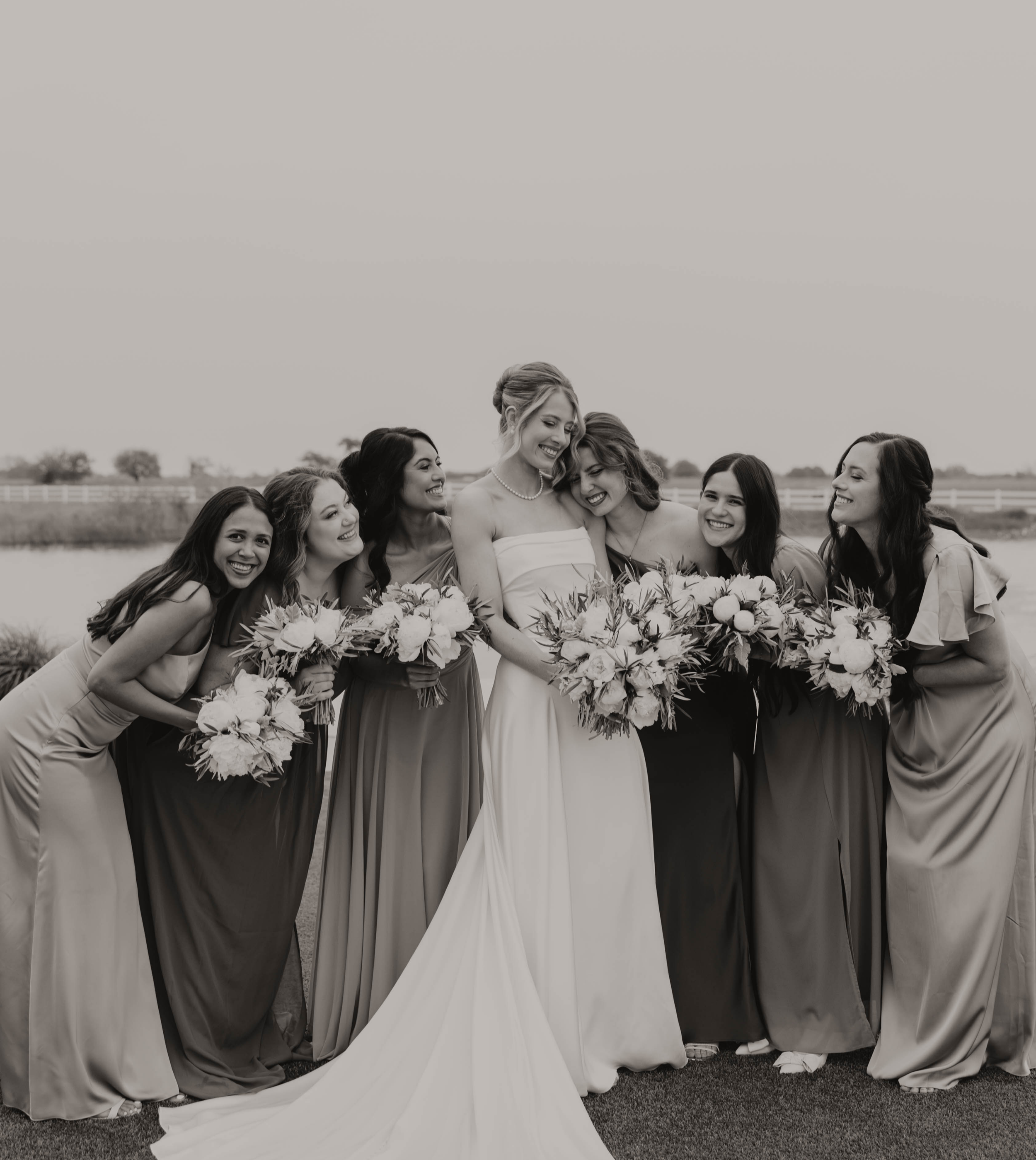 Organisation d'un mariage sur mesure.Photo en noir et blanc d’une mariée entourée de ses demoiselles d’honneur, chacune tenant son bouquet, capturant un moment élégant et complice lors d’un mariage organisé par A&L Events.