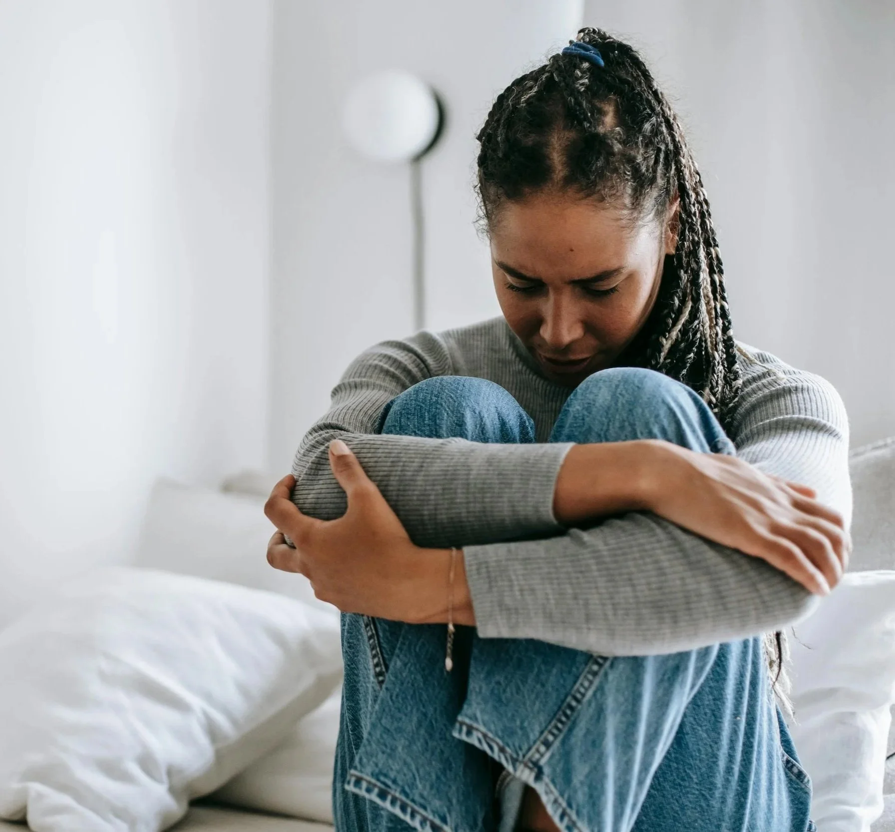 upset woman hugging herself on a bed