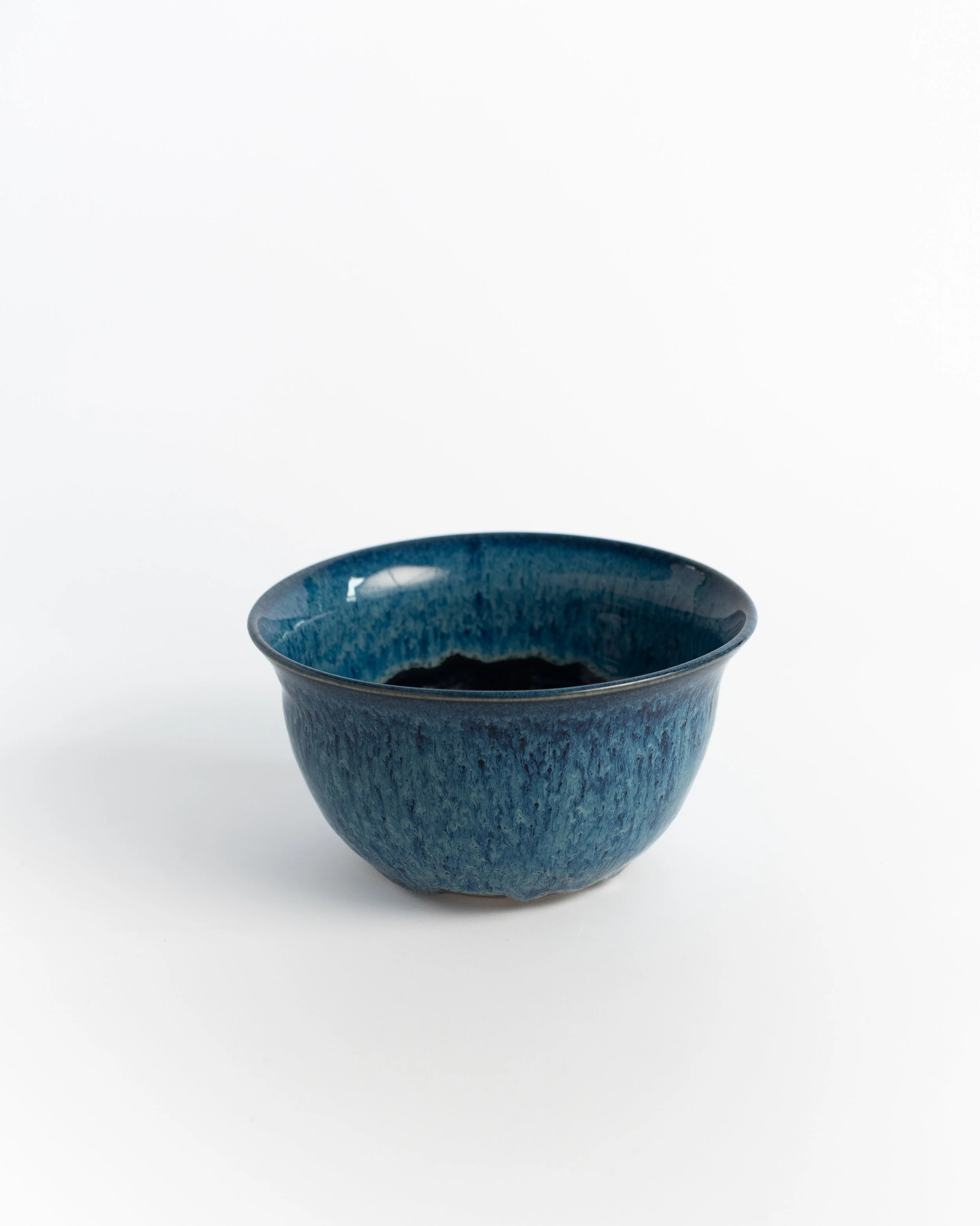 Deep ceramic bowl in mottled cobalt with a flared rim and rich variation throughout.