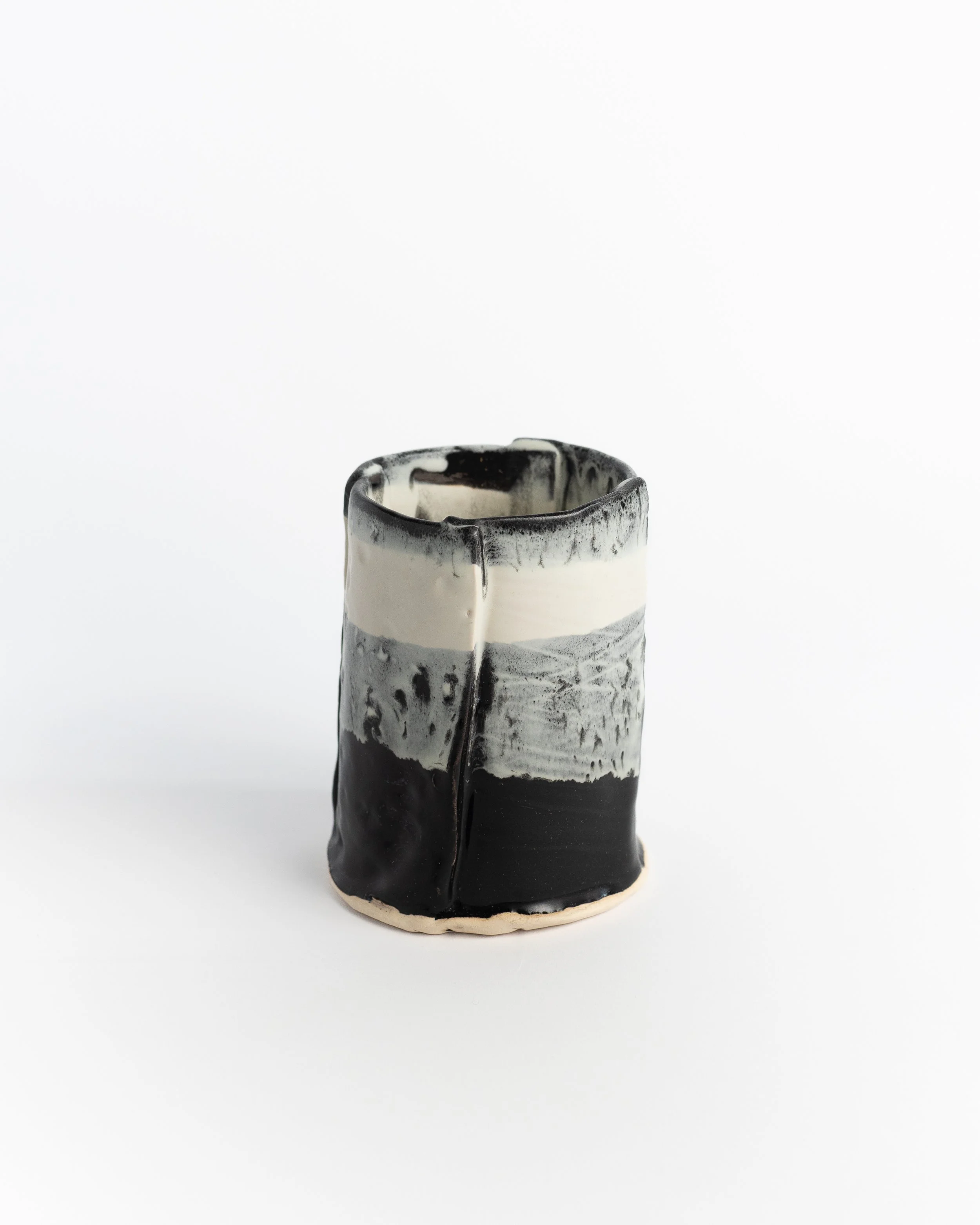 Straight-sided ceramic tumbler in black with a band of cream and grey drifting across the surface.