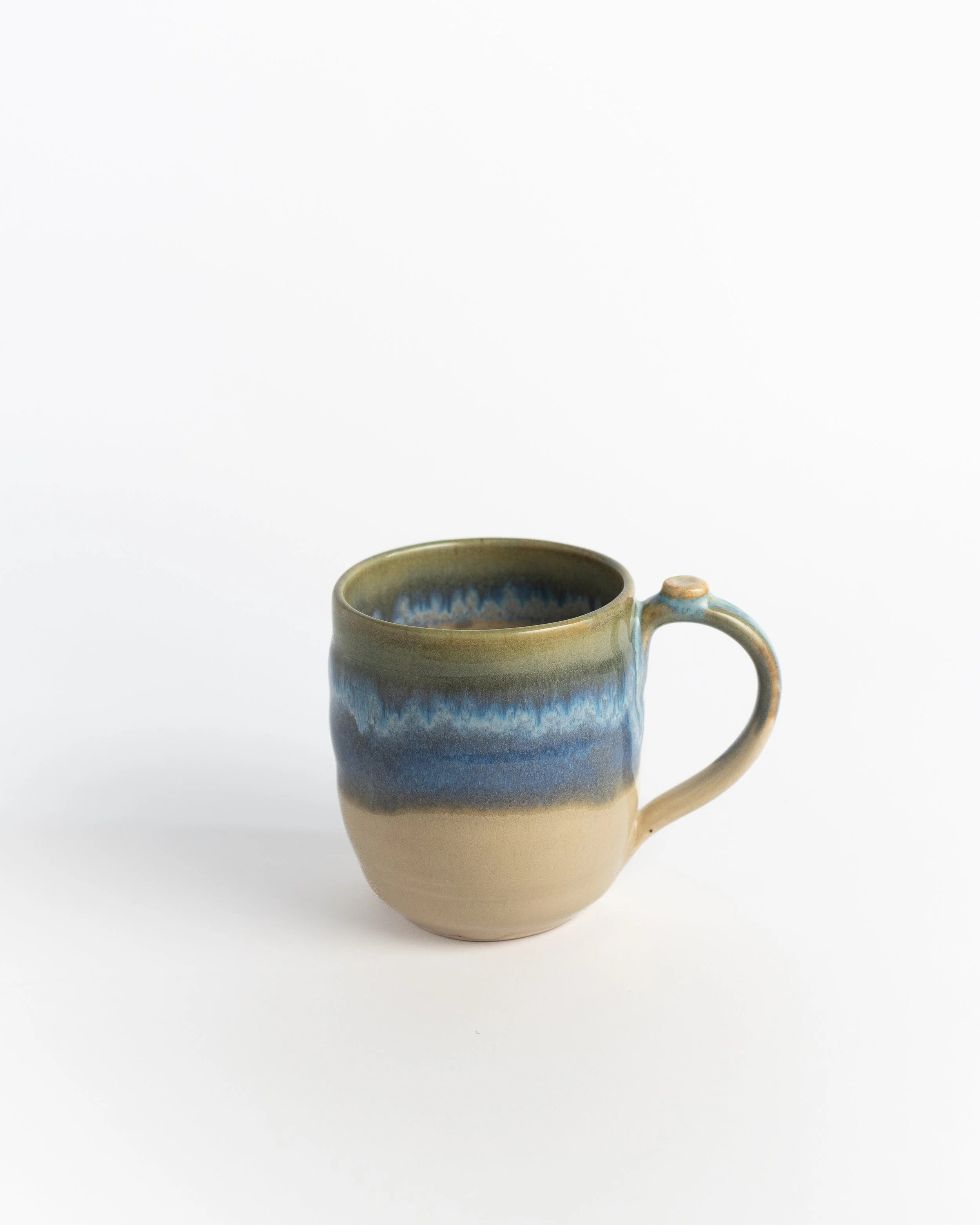 Ceramic mug in natural sand clay with a band of blue and green washing across the middle.