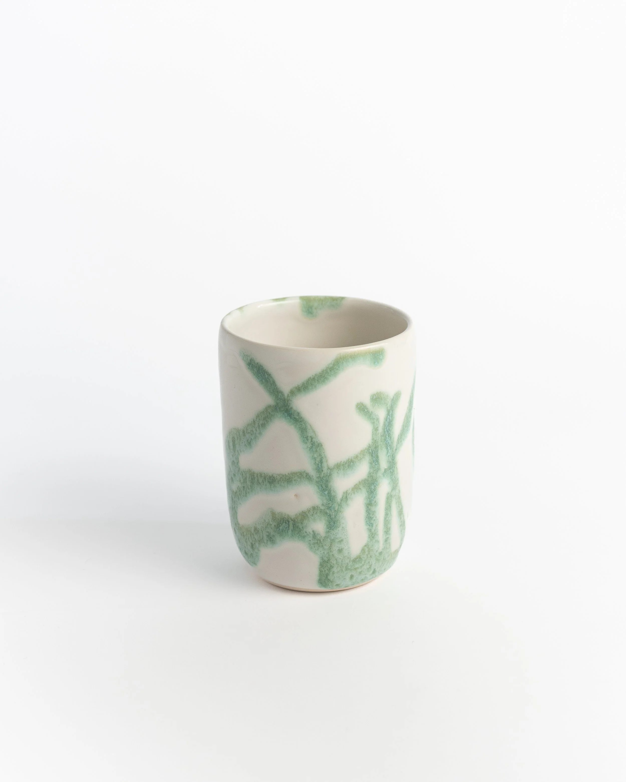 Handleless ceramic tumbler in soft white with green vines brushed freely across the surface.