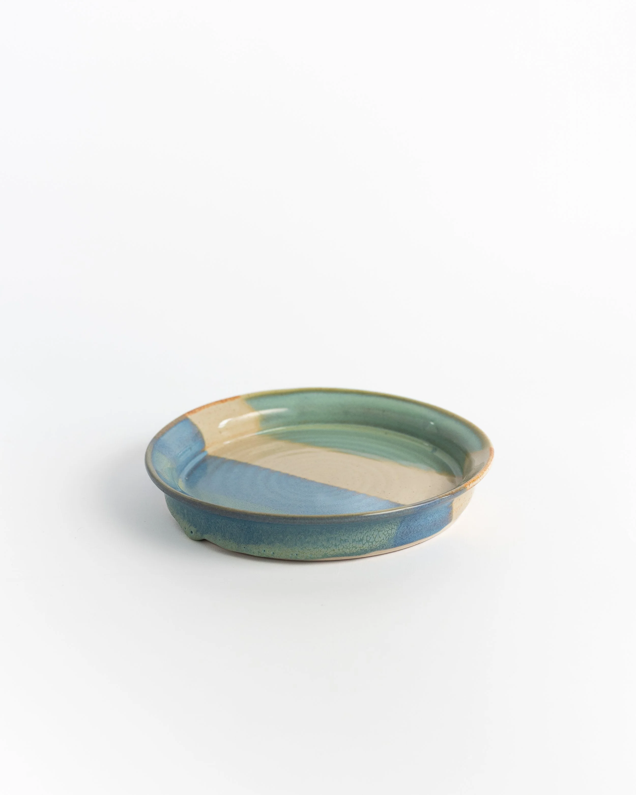 Shallow blue and green ceramic plate seen edge-on, showing the raised rim.