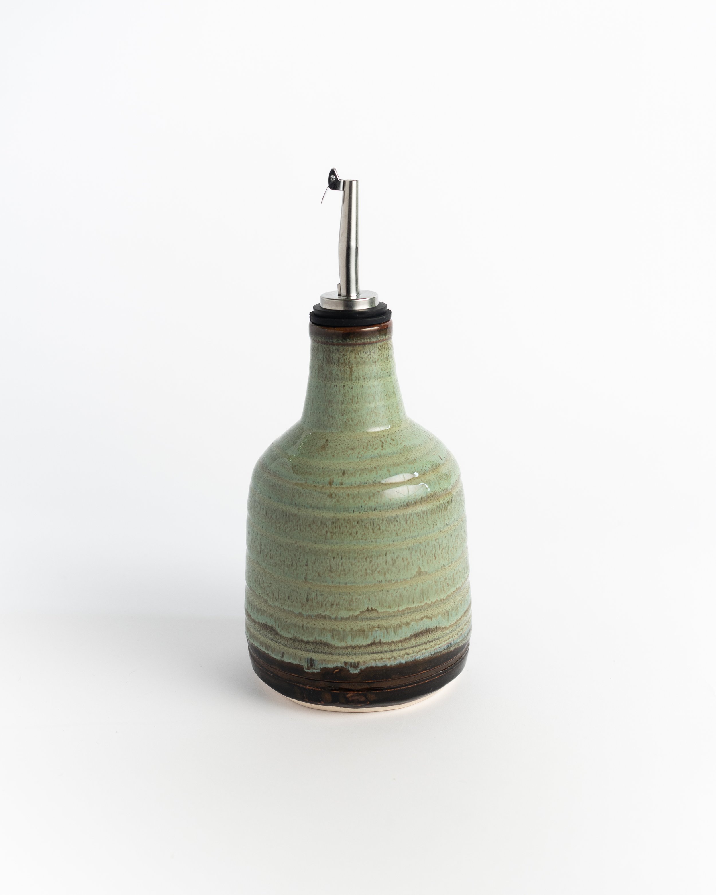 Tall ceramic oil cruet in soft sage green over a dark base, fitted with a stainless pour spout.