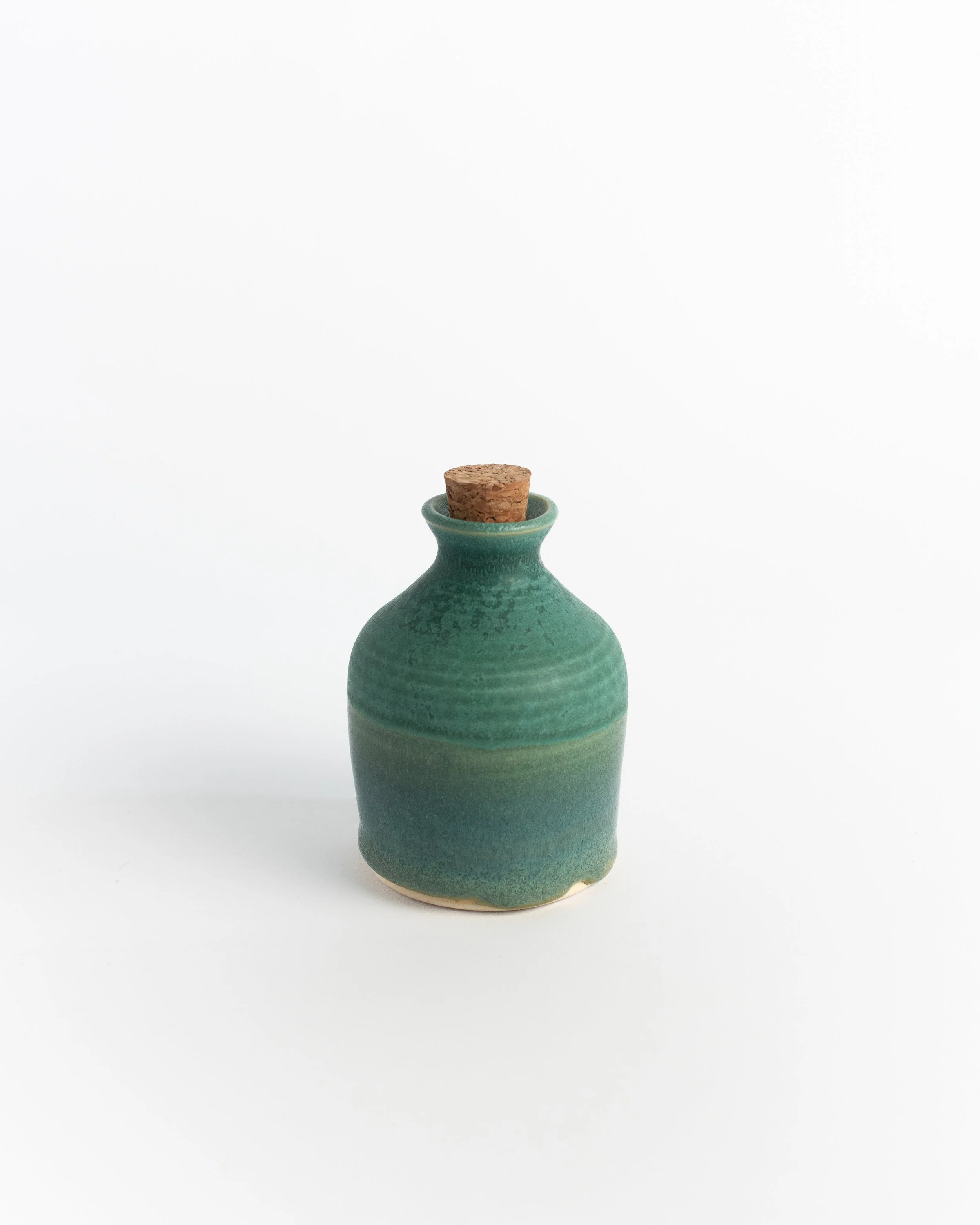 Small corked ceramic bottle in banded teal with a natural cork stopper.