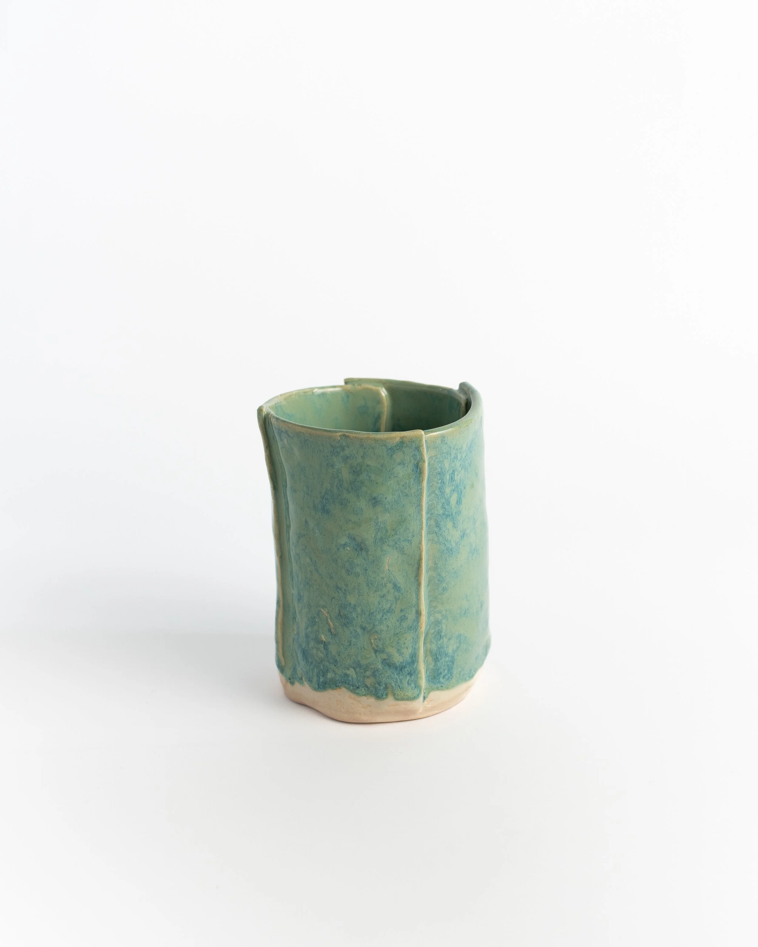 Hand-faceted ceramic cylinder vase in mottled green and teal with crisp carved edges.