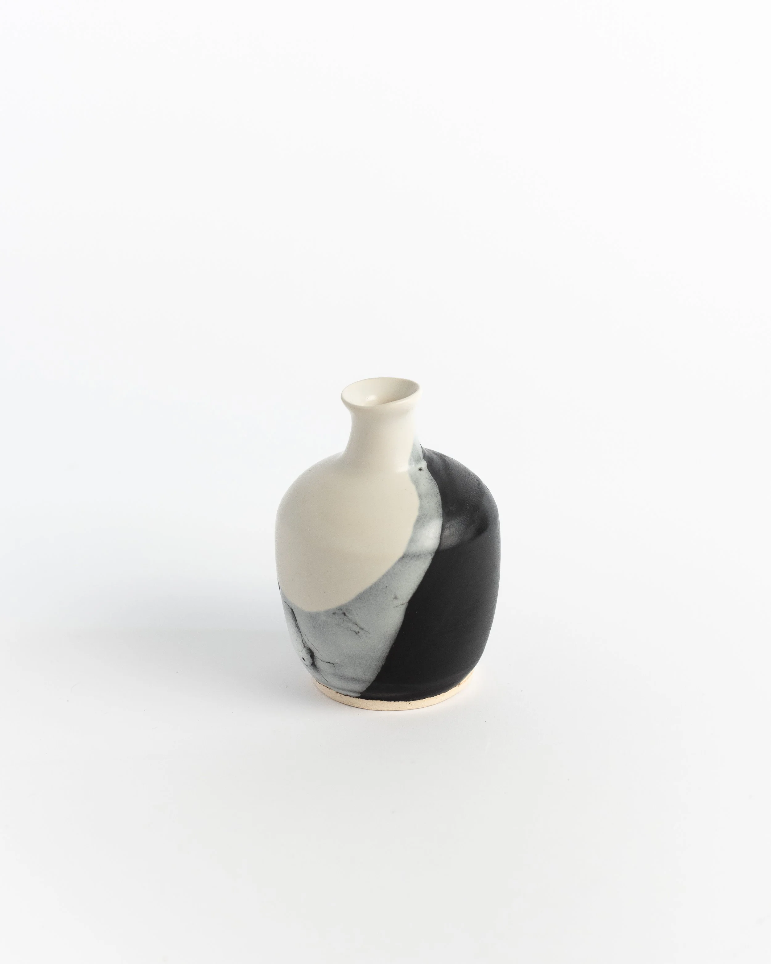 Ceramic bud vase where creamy white swirls into glossy black like polished stone.