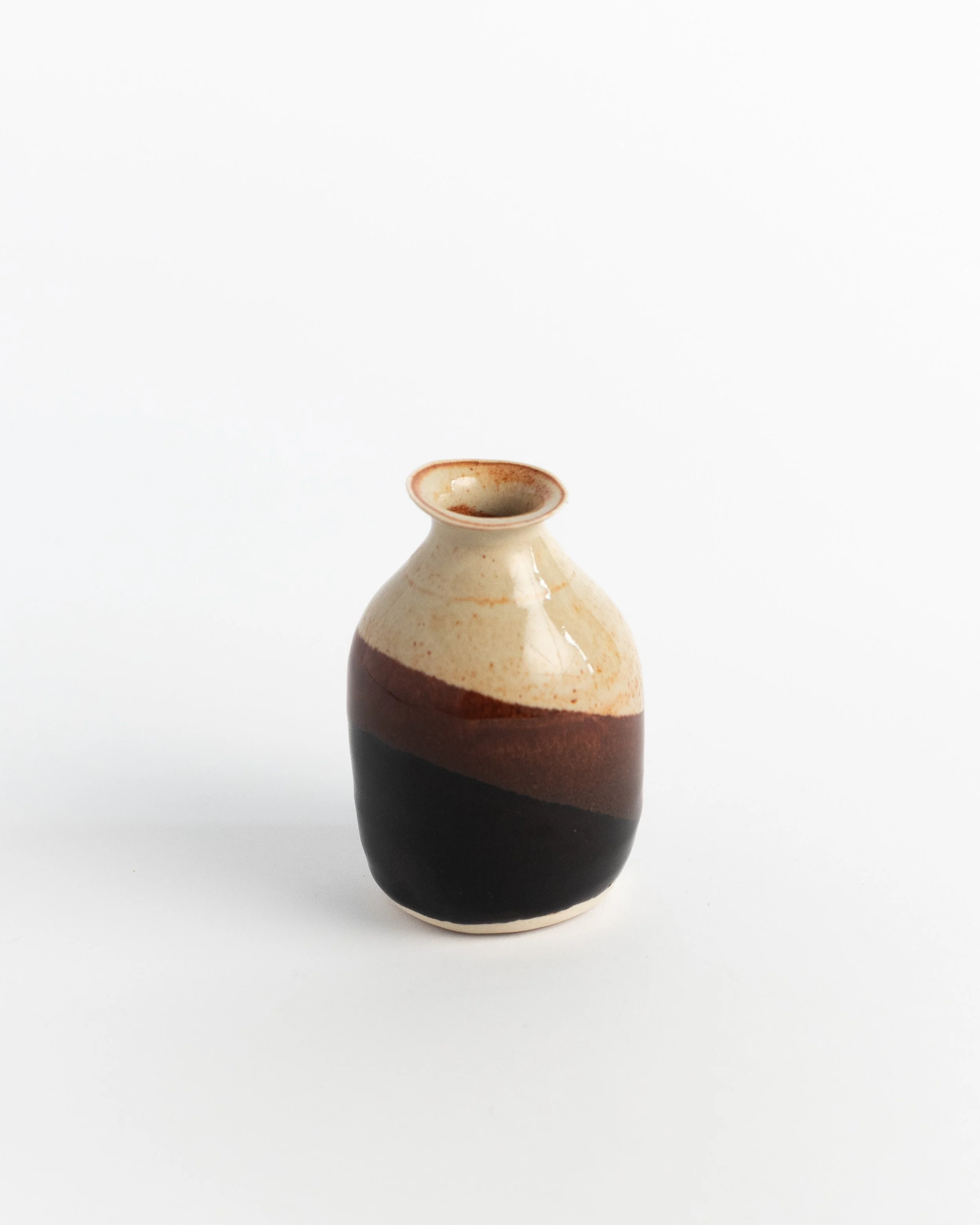 Ceramic bud vase in speckled sand banded with rust and deep black.