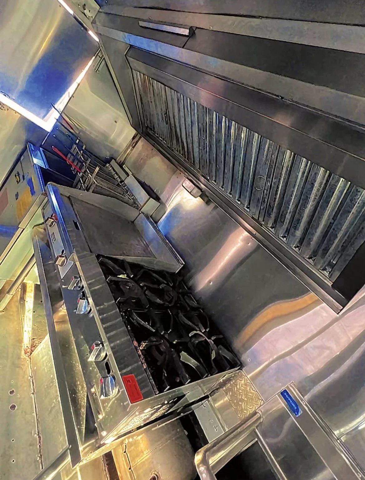 Commercial kitchen with stainless steel appliances and black cooking pots on a stove[ New Jersey]