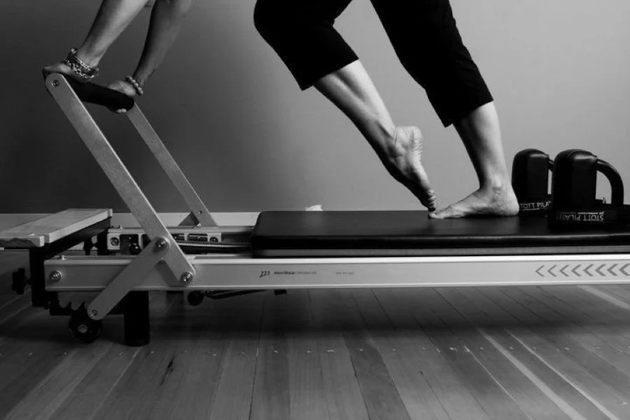 Personne utilisant un appareil de physiothérapie pour refaire la marche sur un tapis roulant avec un pied suspendu.