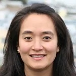 A woman with dark hair smiling, outdoors