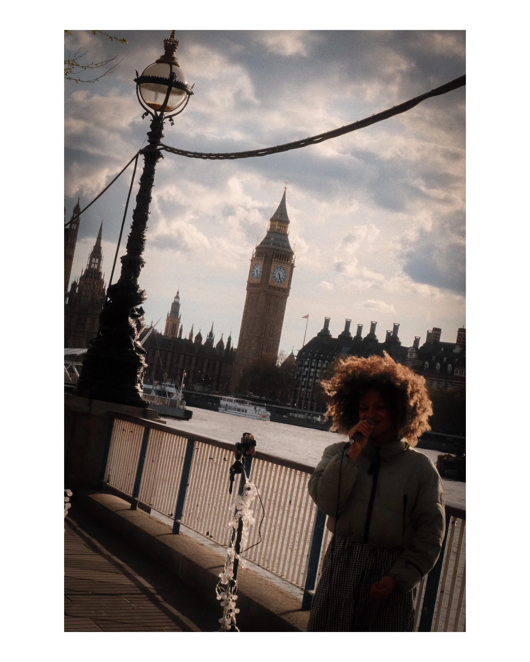 A street singer by Big Ben, her voice echoing along the Thames—capturing the soul of London in a fleeting, authentic moment.