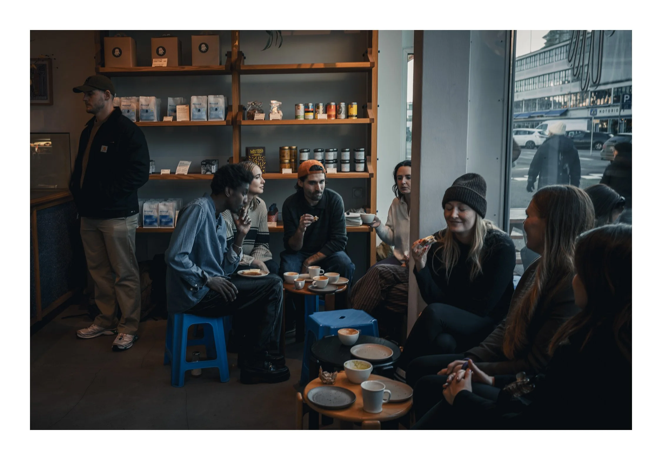 People sit inside the bakery, chatting over fresh pastries and warm coffee while the smell of bread fills the room. Through the window, you can see life passing by outside, but inside everything feels cozy and slow. It’s the kind of place where you w