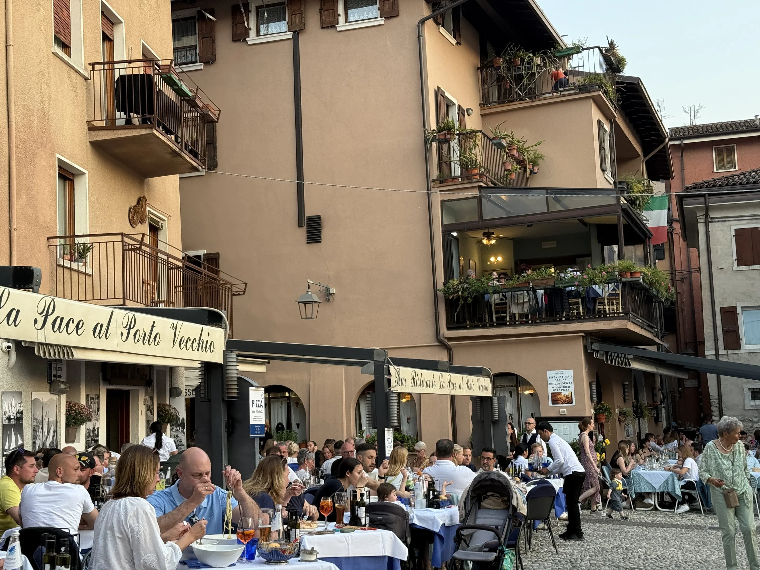 People sit outside, enjoying dinner as the evening settles in.
Soft light, quiet conversations, and shared meals create a relaxed mood.
It’s a moment where time slows down and everyday life feels beautifully simple.
