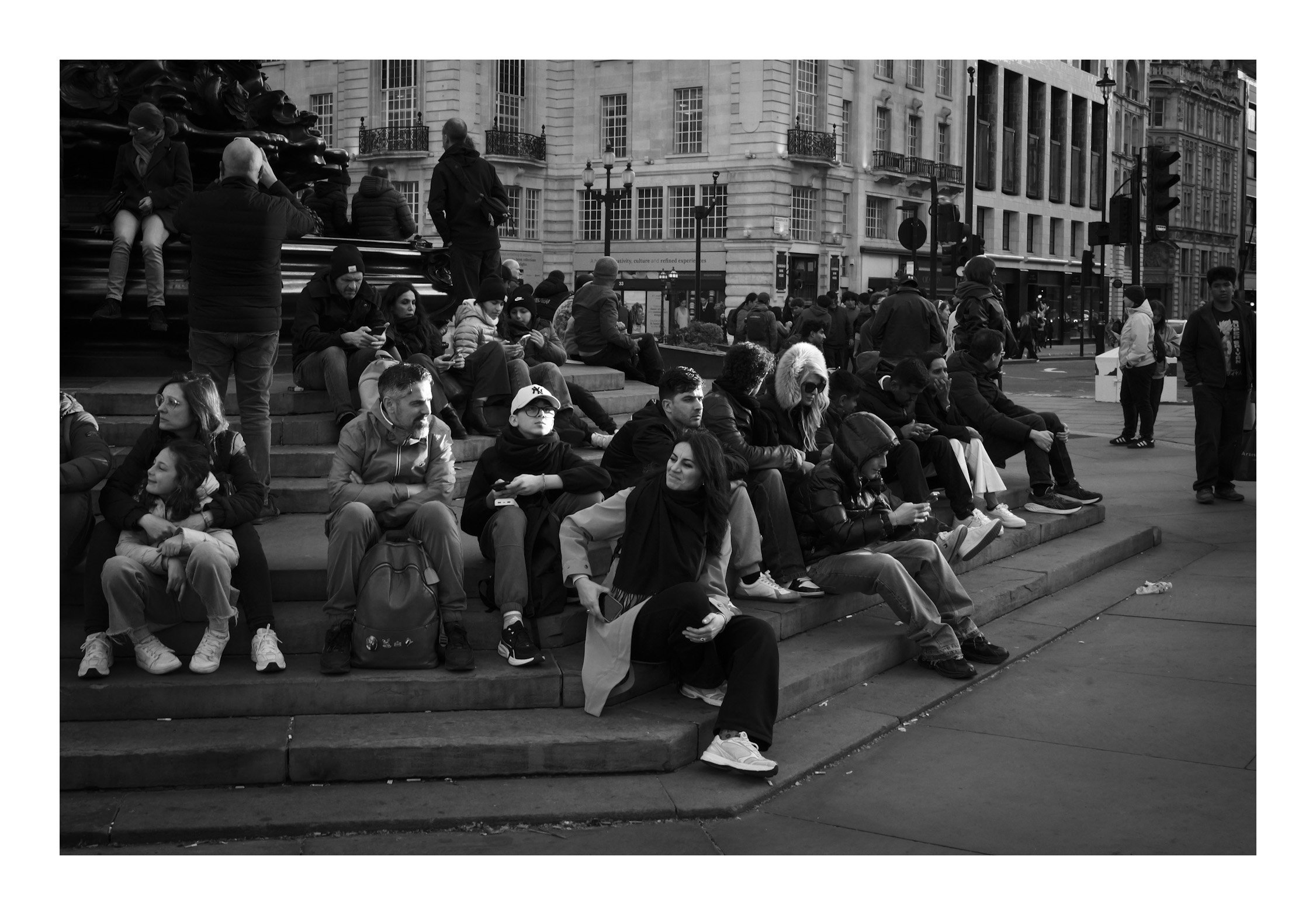 At Piccadilly Circus, people gather and unwind—soaking in the atmosphere as the vibrant energy of London surrounds them.