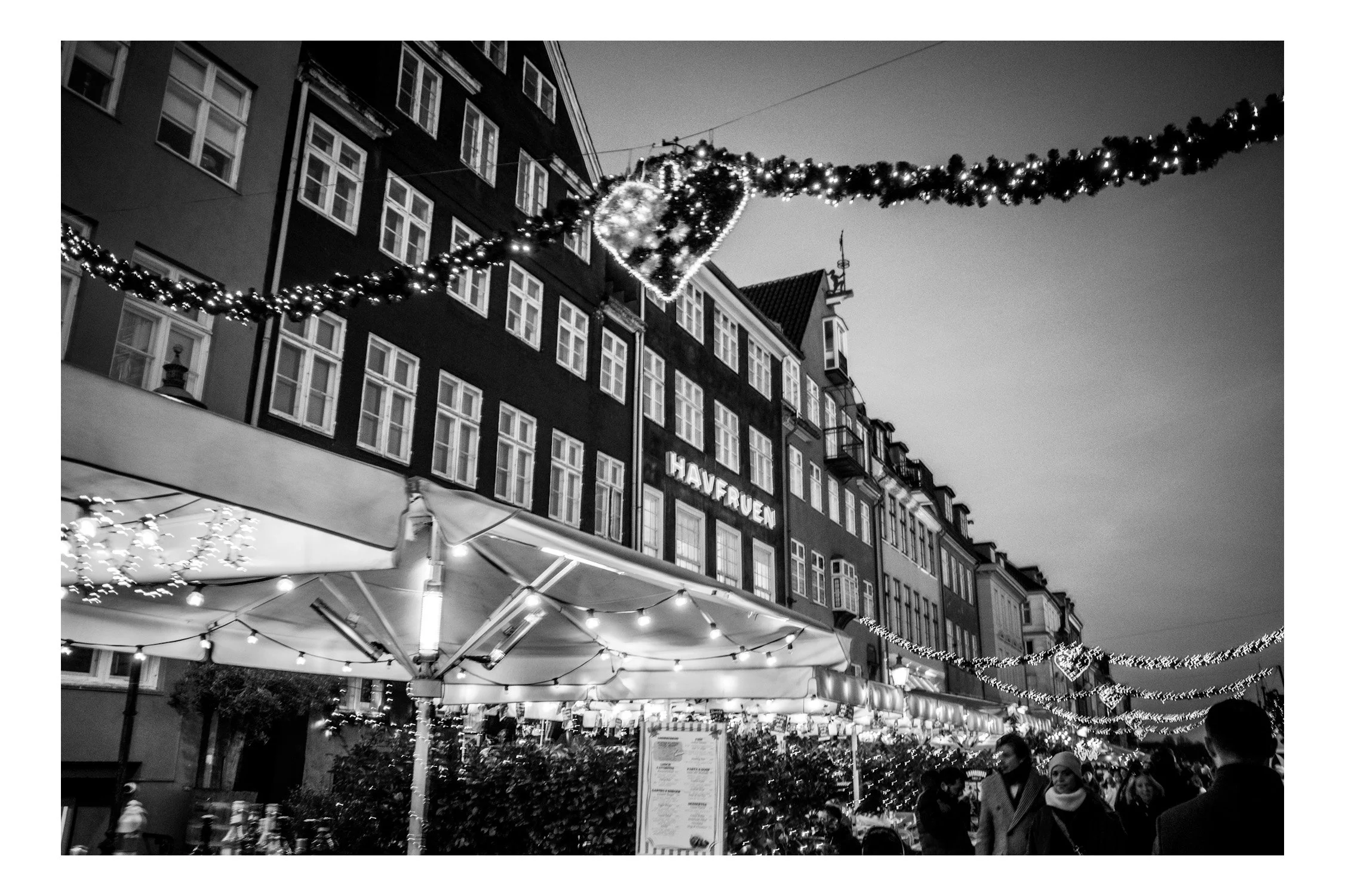 Nyhavn at Christmas feels like a winter fairytale. The colorful houses are wrapped in lights, small wooden stalls sell mulled wine, snacks, and gifts, and the reflections in the water make everything glow.