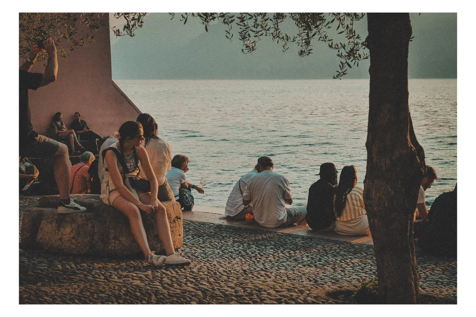 A woman sits on a stone by the water, watching the sunset in silence.
Warm light reflects across the surface as the day slowly comes to rest.
It’s a moment of calm, presence, and quiet reflection.