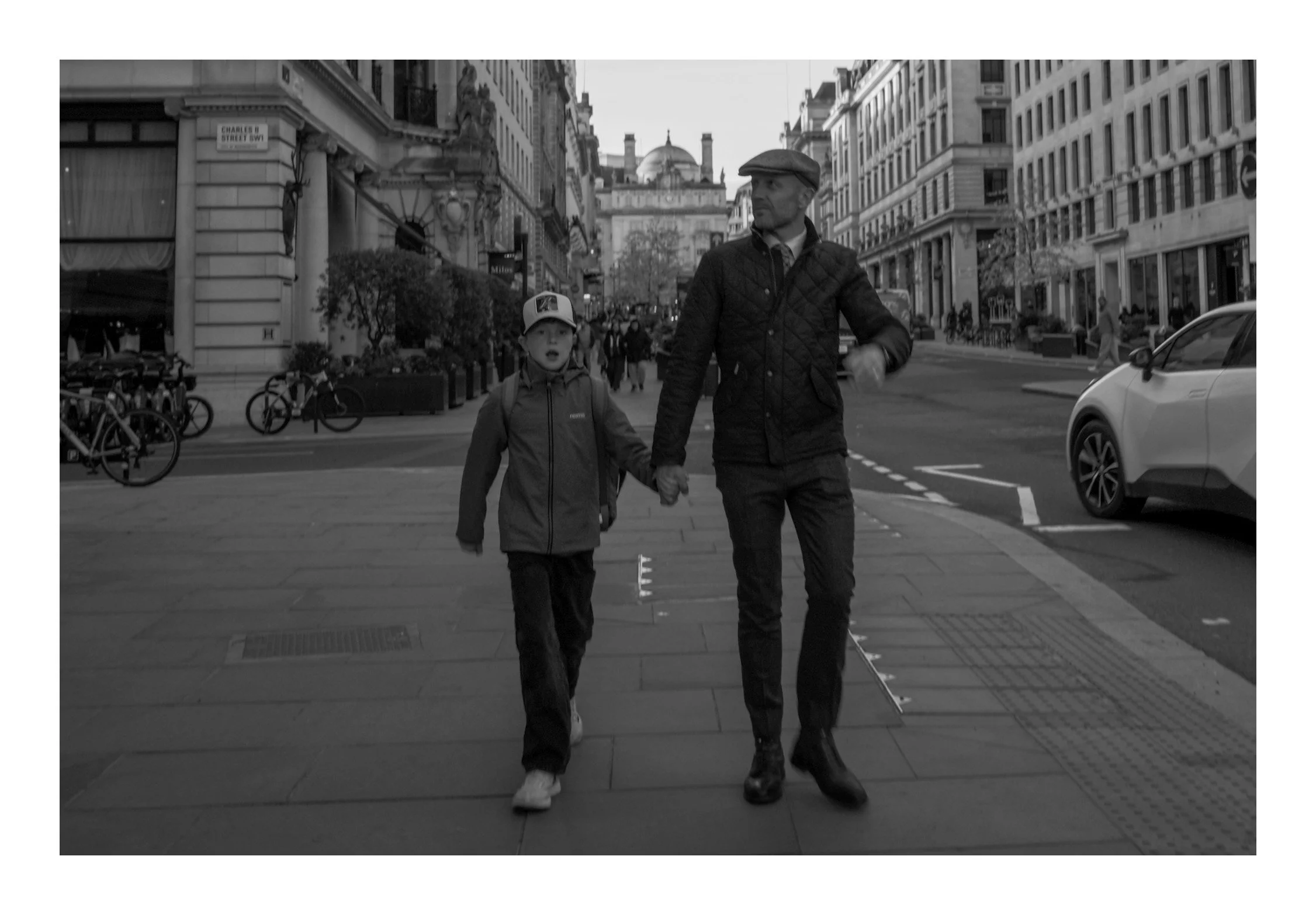 A father and his son walking down the street—capturing a simple, heartfelt moment of connection within the rhythm of the city.