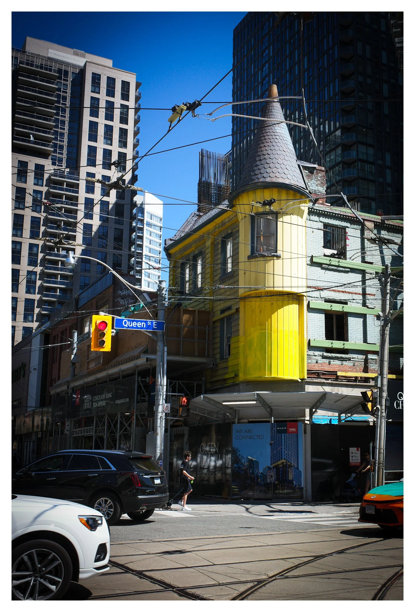 At the corner of Queen Street East, old and new Toronto collide in a single frame. The colorful Victorian house refuses to be overshadowed by the skyline that continues to grow around it.