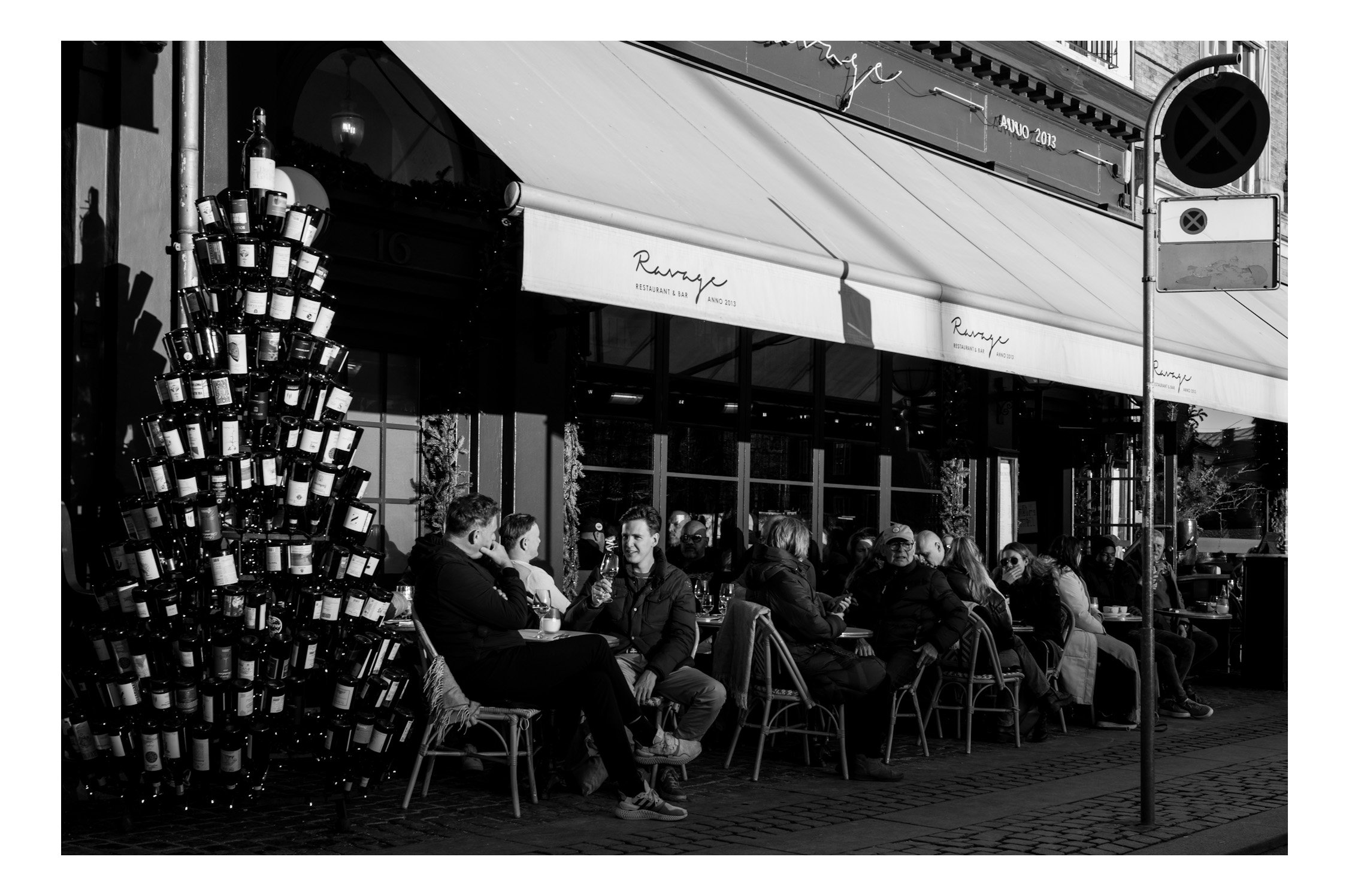 People sit outside at the café, wrapped in blankets, sipping coffee and chatting while the world slowly passes by. Laughter, clinking cups, and the smell of fresh pastries fill the air. It feels calm, cozy, and like everyone has time to simply enjoy 