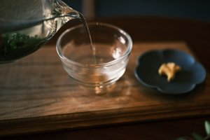 Hot tea being poured into a clear glass cup