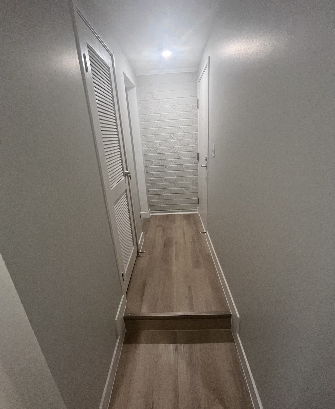 Bright, modern hallway featuring updated flooring, fresh paint, and a clean accent wall that adds depth and character.
