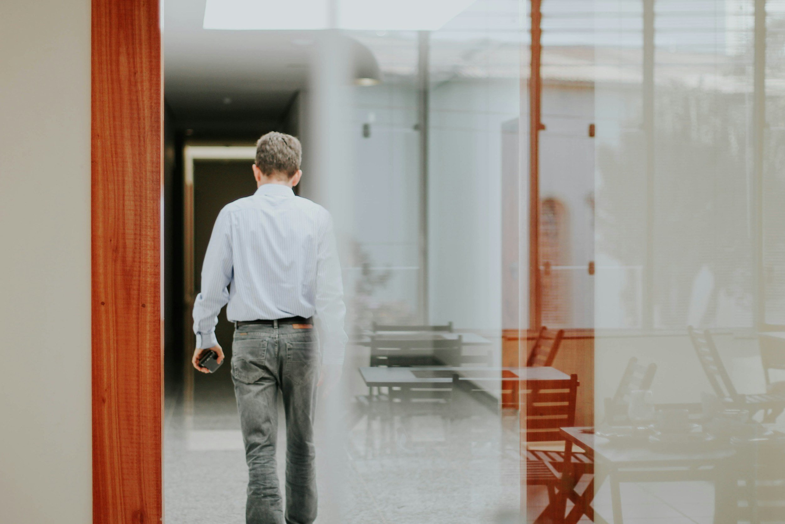 Person walking down a corridor while holding a phone.
