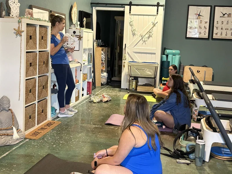 Christine LaM'ee holding an anatomical model of a pelvic and speaking in front of a group of women.