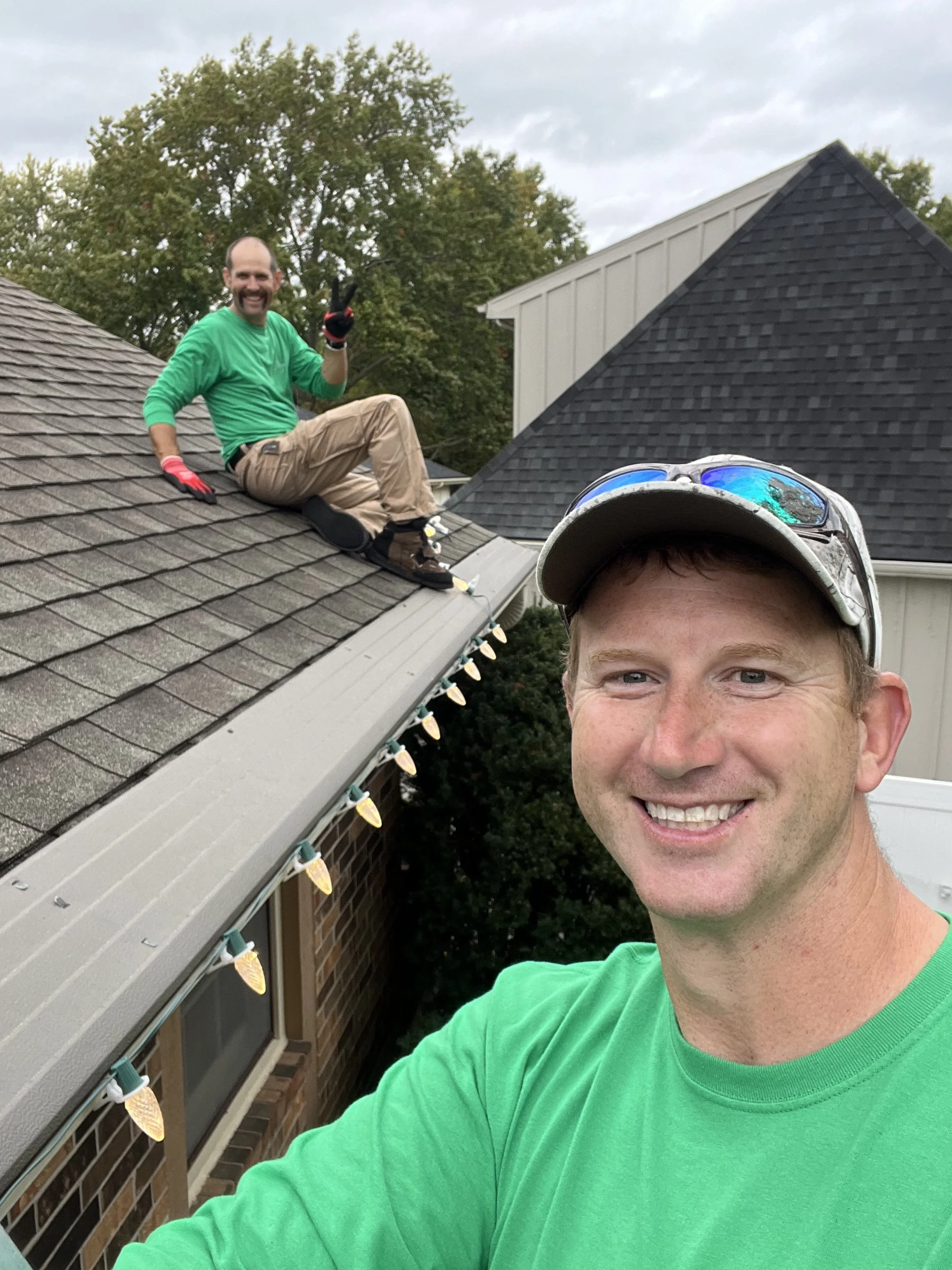 2 guys hanging christmas lights on a roof