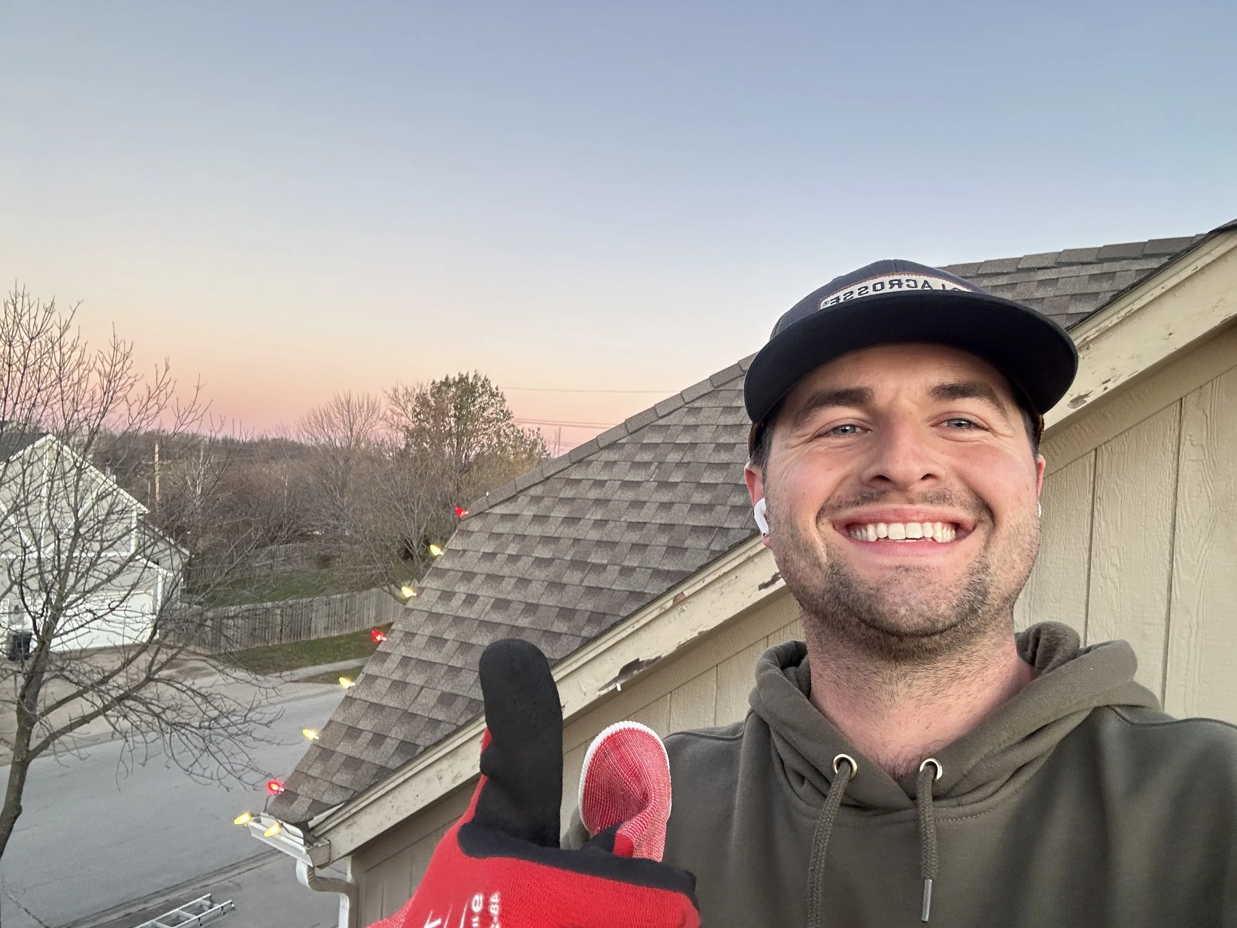 Christmas Light installer on roof giving a thumbs up
