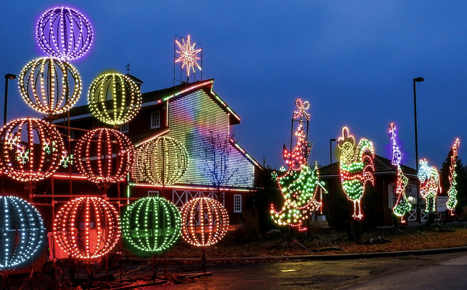 Colorful Christmas lights display with illuminated ornaments and festive figures outside a building at night.