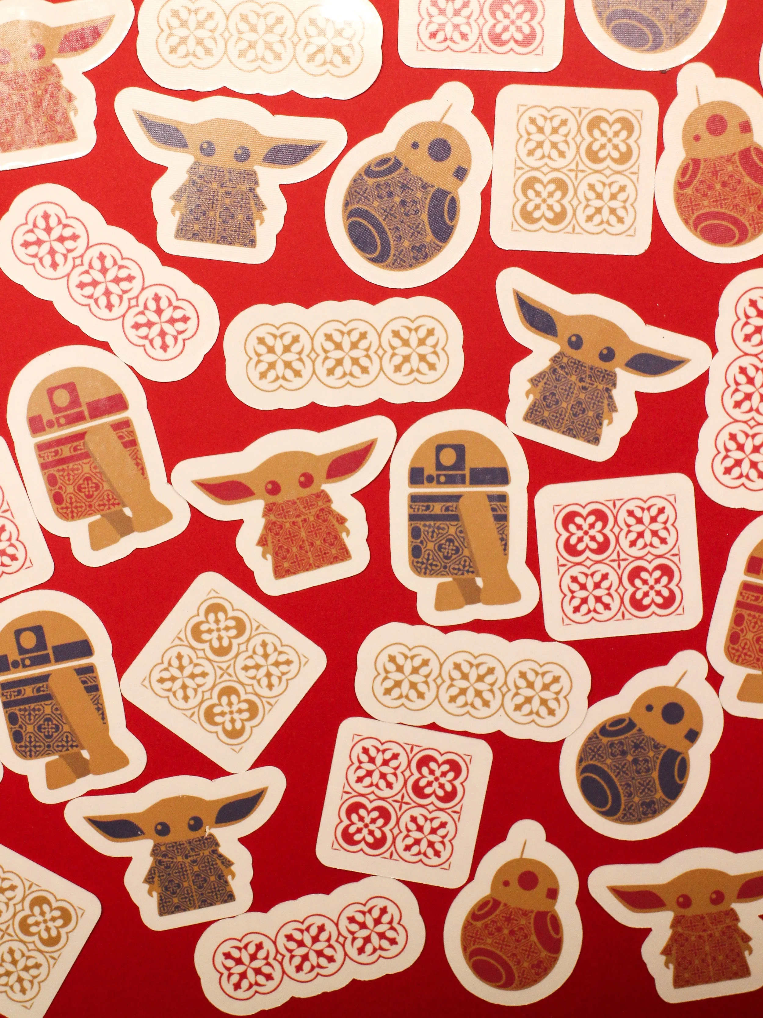 Collection of stickers featuring Star Wars baby Yoda, droids, and patterned tiles, on a red background.
