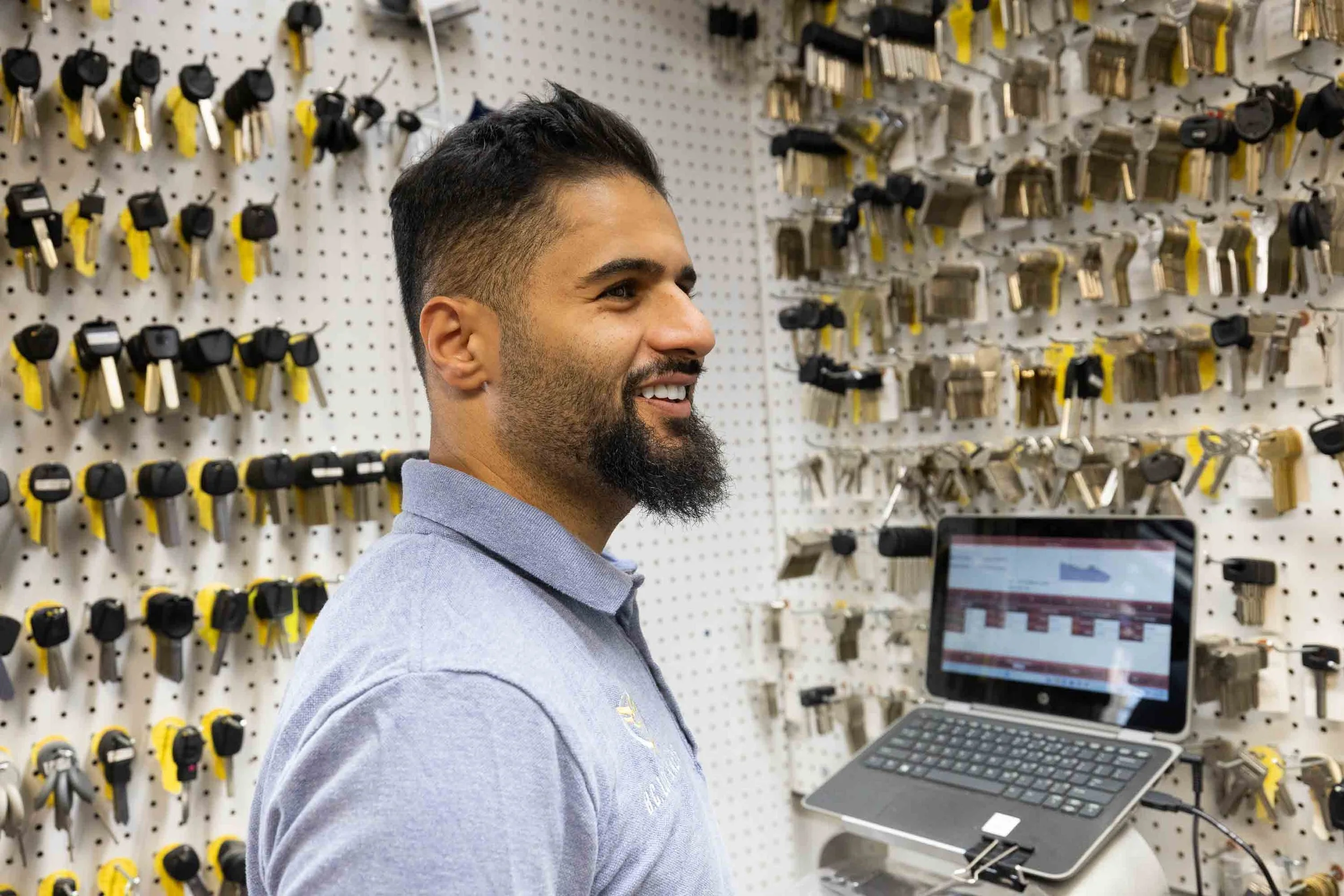 Locksmith in a Harrisonburg VA shop selecting keys from a wall of key blanks for residential and commercial key duplication.