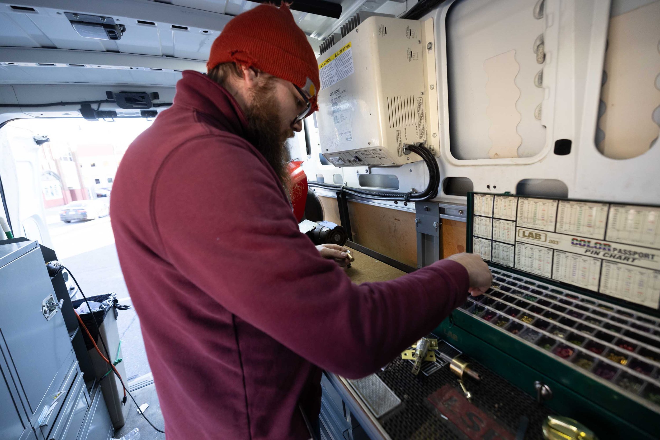 Locksmith performing key duplication work at a Harrisonburg VA shop, preparing keys with a key cutting workstation.