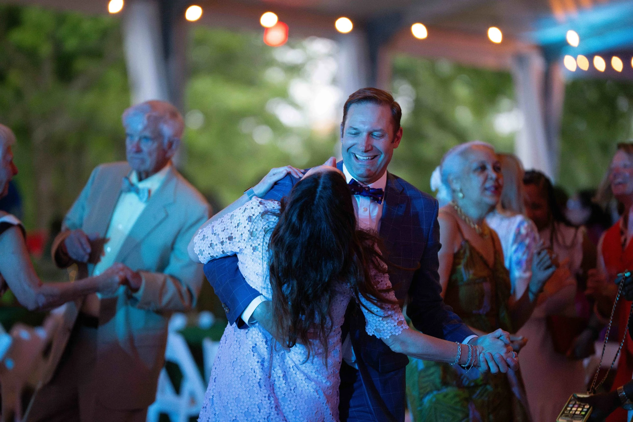 Candid outdoor evening event photography featuring a couple dancing under string lights at a garden venue in Lexington, KY, by 859 Photography.