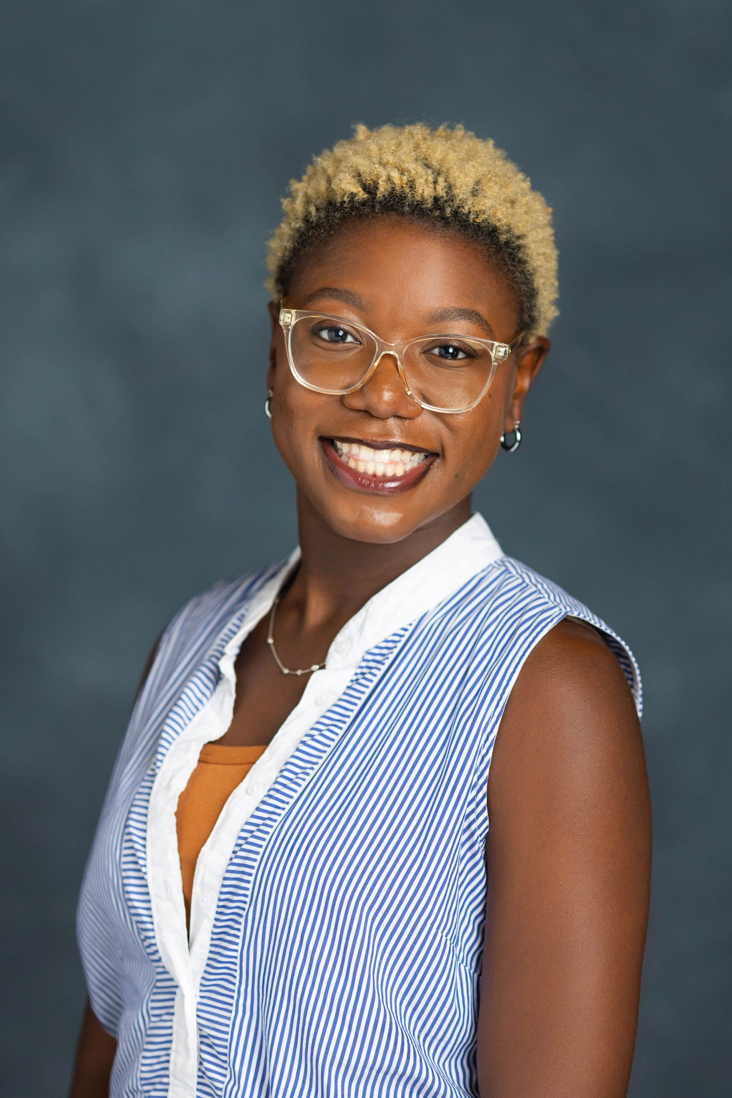 Professional studio headshot of a woman with curly blonde hair against a dark grey background, captured by 859 Photography in Lexington, KY.