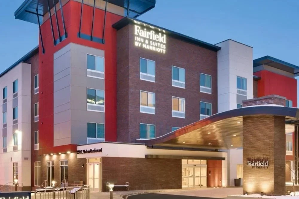 Exterior view of a Fairfield Inn & Suites by Marriott hotel at dusk, showing the building with illuminated sign and entrance canopy.