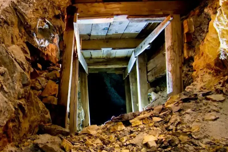 View looking down into a mine shaft with wooden reinforcements and rocky walls.