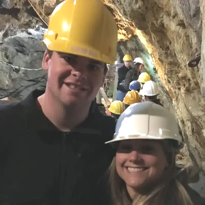 Man riding a fat tire mountain bike on snowy trail, wearing red jacket, helmet, and sunglasses, with snow-covered trees in the background.
