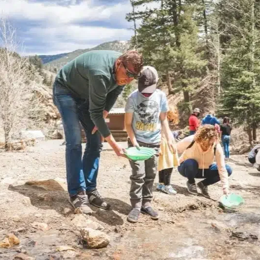 People collecting water from a river in a forested area.