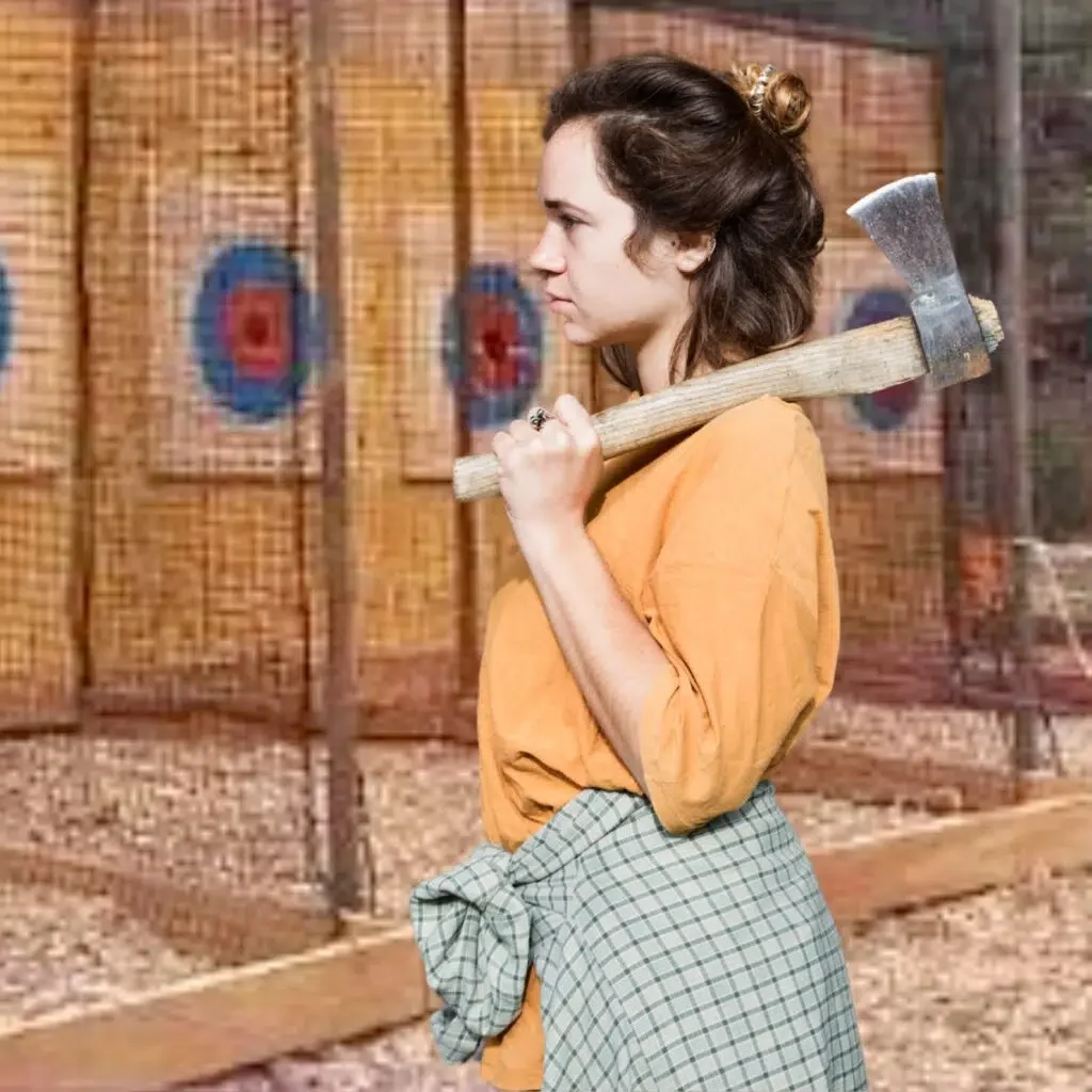 Woman dressed in period costume holding an axe on her shoulder, with an archery target in the background.