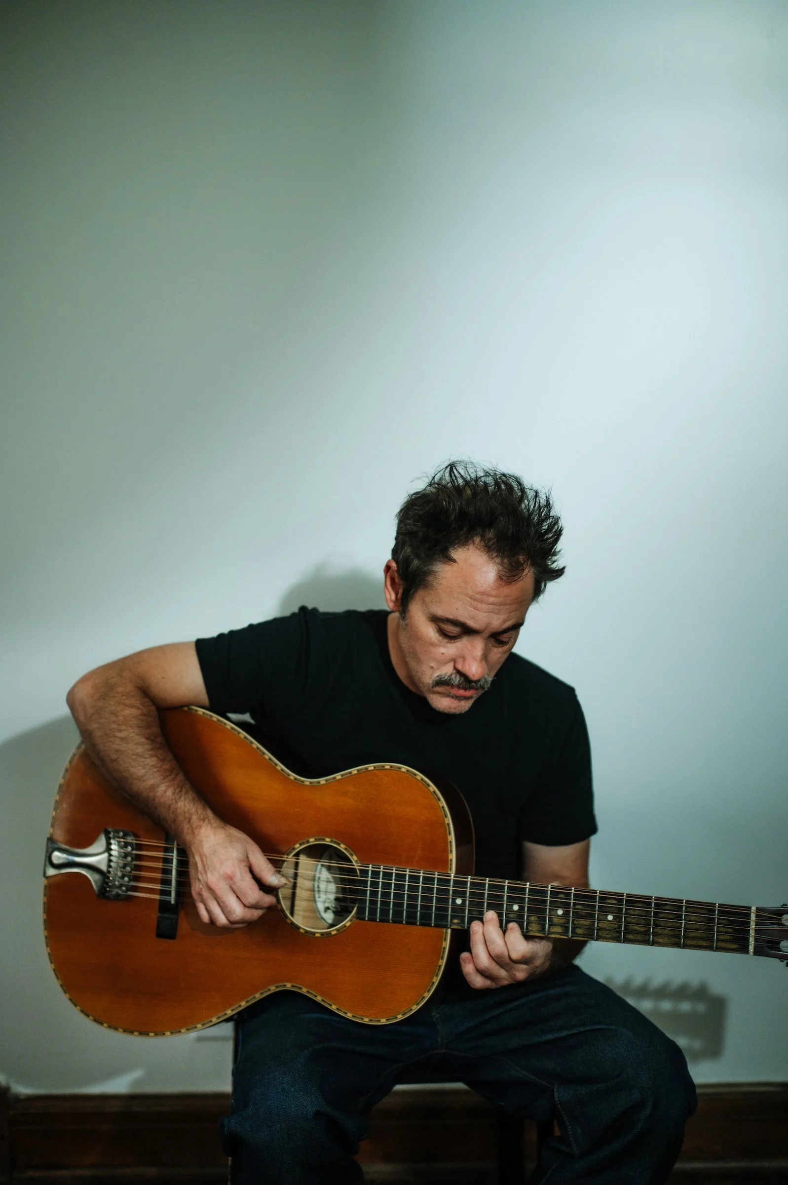 Todd Albright seated and holding a twelve string guitar