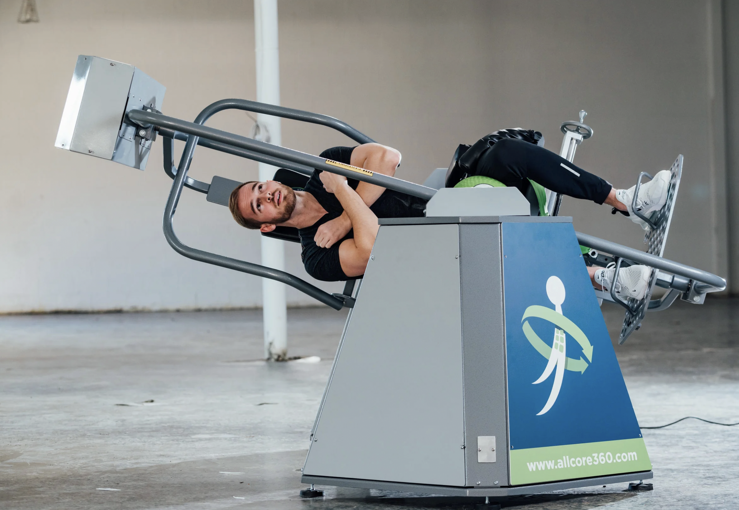 A man lying on a medical rehabilitation device in an industrial setting.