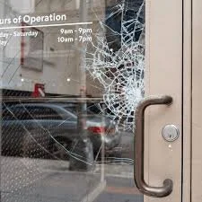 Broken glass door with shattered window and visible cracks.