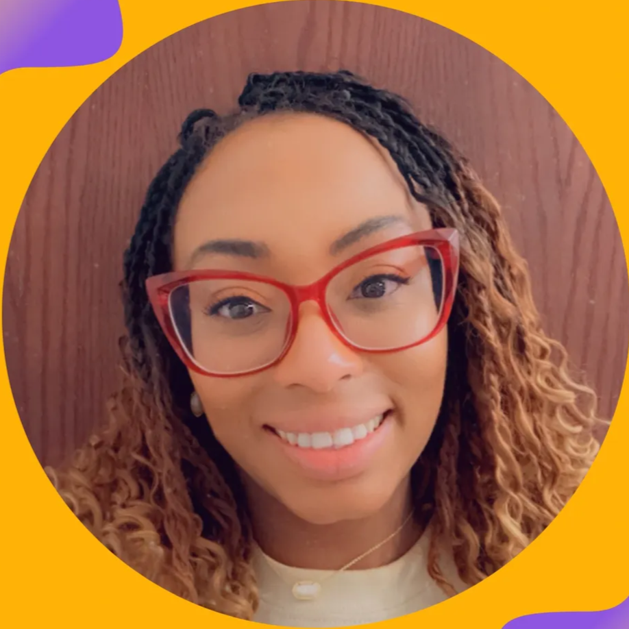 Alyssa Morrison headshot: A woman with curly hair and red glasses smiling for a selfie in front of a wooden background.
