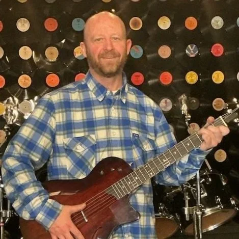 Photo of John Prendergast holding a guitar