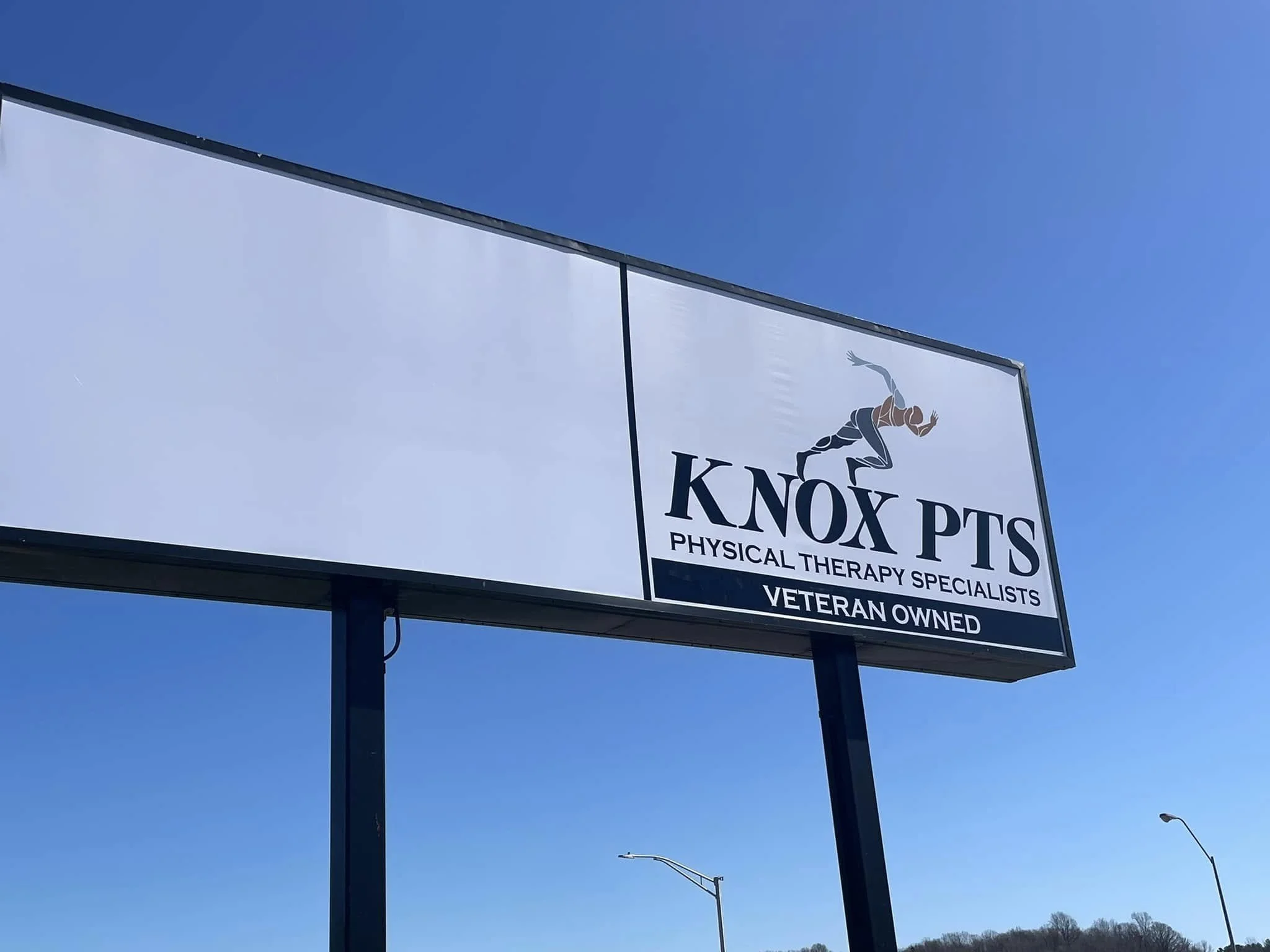 Billboard advertising Knox PTS, a veteran-owned physical therapy specialty business, featuring a running figure logo against a blue sky.